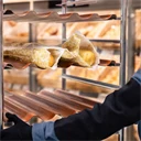 Ung kvinna som jobbar i brödavdelningen i en matbutik