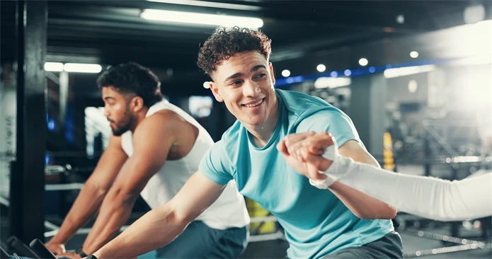 Ung man tränar på träningscykel på gym. 