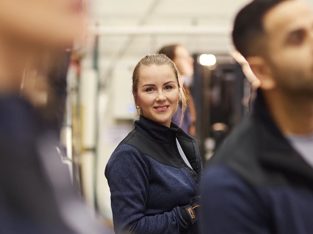 Porträtt av kvinnlig lagerarbetare bland kollegor.