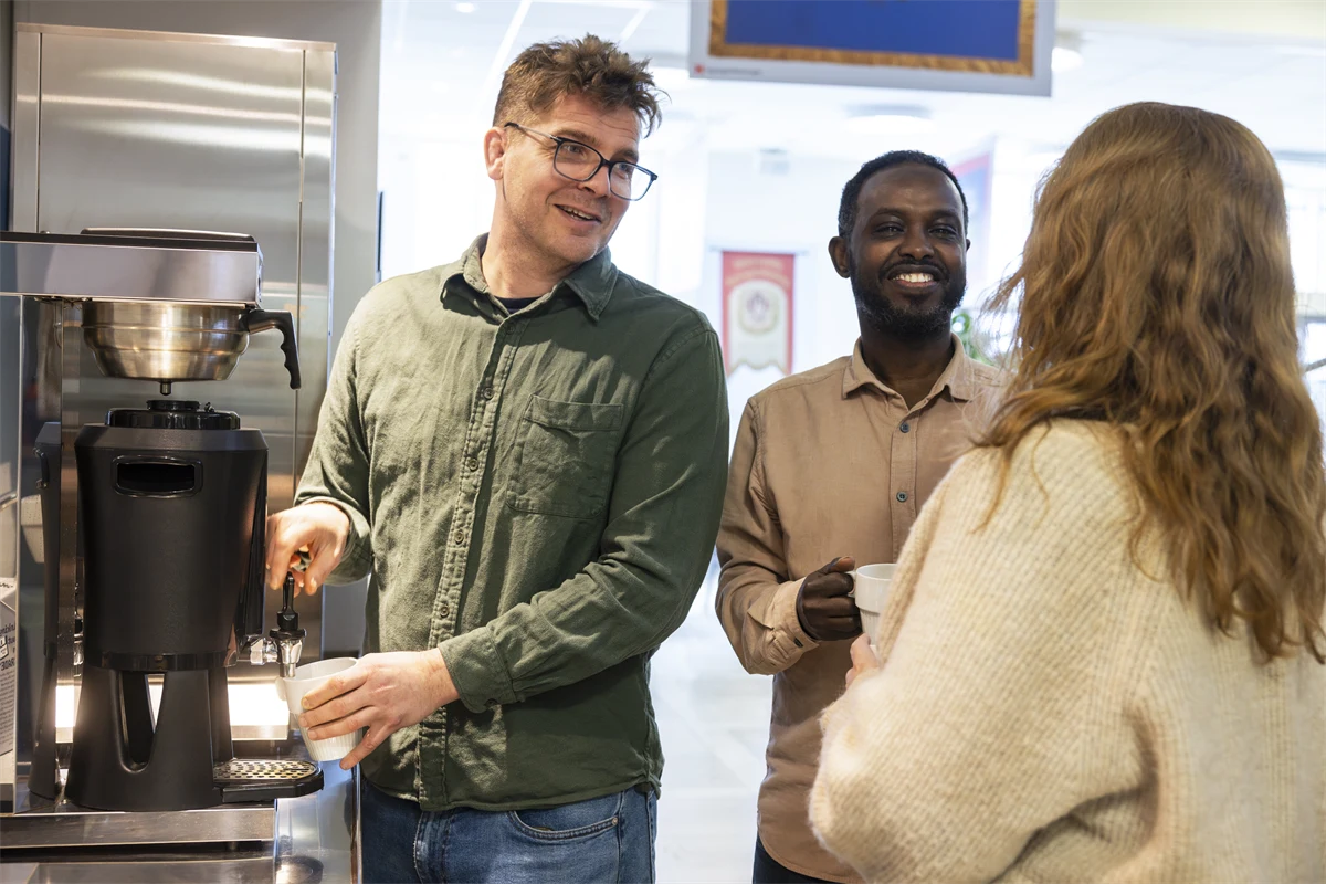 Tjänstemän i avslappnat samtal vid kaffeautomaten