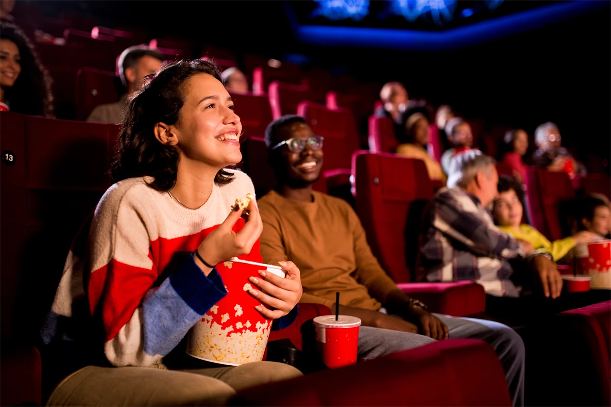 Ung kvinna går på bio och äter popcorn.