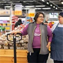 Ett samtal mellan två glada kvinnor som jobbar i matbutik.